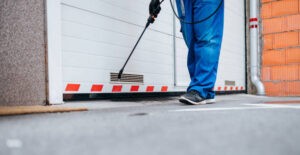 Manual worker disinfecting garage, showcasing commercial pest control service in action.