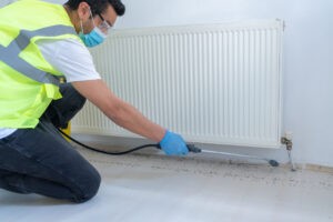 Person in safety gear inspecting radiator amid scattered debris.